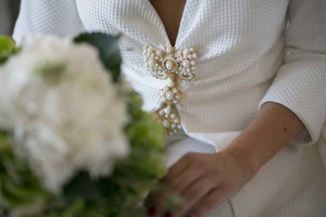 Vestido de novia con detalles de alta costur y ramo de flores blancas